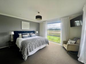 a bedroom with a bed and a window and a chair at Benrose Park in Palmerston North