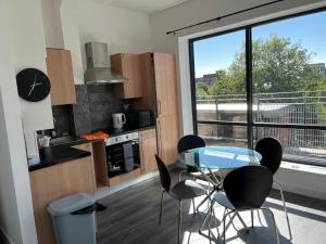 eine Küche mit einem Glastisch und Stühlen sowie einem Fenster in der Unterkunft Mordern Apartment in City Center in Manchester