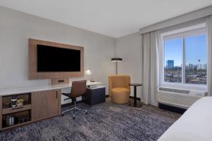 a hotel room with a television and a desk with chairs at DoubleTree by Hilton Las Vegas East Flamingo in Las Vegas