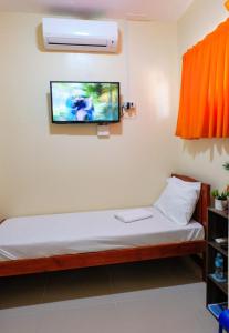 Zimmer mit einem Bett und einem TV an der Wand in der Unterkunft Downtown Suites CDO in Cagayan de Oro