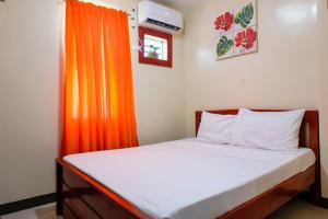 a bedroom with a bed with an orange curtain at Downtown Suites CDO in Cagayan de Oro