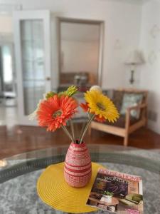 Glengarry Haus Home Away From Home في ميسيساوغا: مزهرية حمراء مع الزهور على طاولة زجاجية