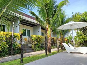 une maison avec des palmiers, une chaise blanche et un parasol dans l'établissement Vivo Siargao, à General Luna