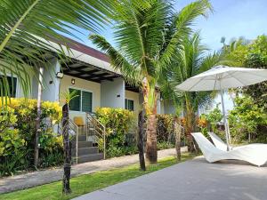 a house with palm trees and a white chair and an umbrella at Vivo Siargao in General Luna