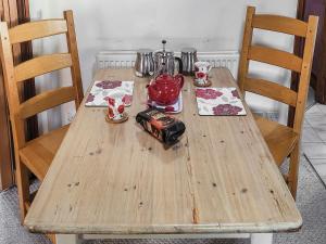 a wooden table with two chairs and a tea pot on it at Elm Barn View in Freethorpe