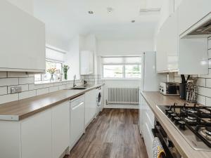 Dalry的住宿－Holmbyre Smithy，白色的厨房设有水槽和炉灶。