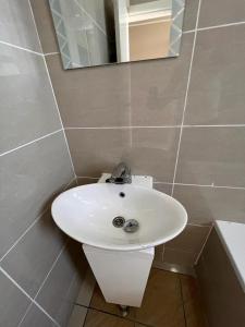 a bathroom with a white sink and a mirror at ZIRICH PROPERTIES EAST LEGON in Accra