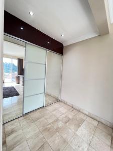 an empty room with glass doors and a tiled floor at ZIRICH PROPERTIES EAST LEGON in Accra