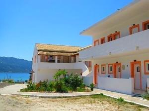 a large white house with orange doors and the water at House Anastasia in Agios Georgios Pagon