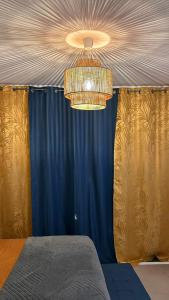 ein Schlafzimmer mit einem blauen Vorhang und einem Kronleuchter in der Unterkunft Le B96 in Cayenne