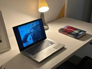a laptop computer sitting on a desk next to a book at Loft Style Partition Room in Shared Apartment in Al Barsha 1 Near MOE Metro in Dubai