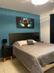 a bedroom with a bed and a blue wall at Loft atardecer in Uruapan del Progreso