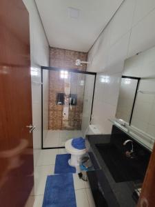uma casa de banho com um chuveiro e um WC com alcatifa azul em Villas da serra 3 em Lagoa Nova