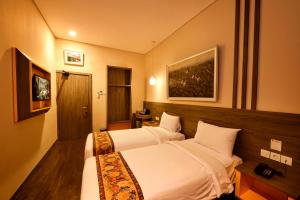 a bedroom with two beds and a painting on the wall at Super 8 by Wyndham Solo in Solo