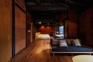 um quarto com uma cama e um sofá num quarto em 浜崎の宿萩別邸 em Hagi