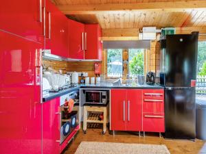 uma cozinha com armários vermelhos e um frigorífico preto em The Cabin Cefn Mawr em Highgate
