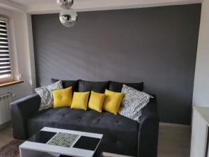 a black couch with yellow pillows in a living room at Apartament przy Parku in Żywiec