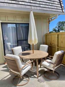 einen Tisch mit Stühlen und einem Sonnenschirm auf einer Terrasse in der Unterkunft OBX Dreamin’ in Kitty Hawk