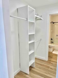 un armario blanco con estanterías blancas en el baño en OBX Dreamin’ en Kitty Hawk