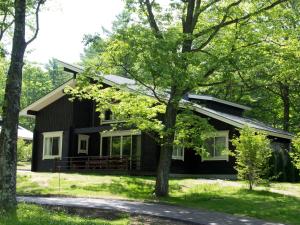 a black house with a tree in front of it at The Prince Villa Karuizawa in Karuizawa