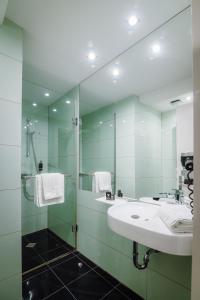 a bathroom with a sink and a shower with a mirror at Plaza V Hotel in Târgu-Mureş