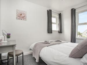 a white bedroom with a bed and a desk at Number One in Saint Dennis