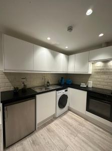 eine Küche mit weißen Schränken und einem Geschirrspüler in der Unterkunft Home-like 1-BR flat in Victoria in London