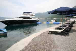 a yacht is docked in the water with chairs and umbrellas at Apartments Villa Jelena in Tivat