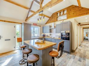 a kitchen with wooden ceilings and a large island with bar stools at The Old Stables in Cumberworth