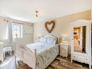 a bedroom with a white bed and a heart mirror at The Old Stables in Cumberworth