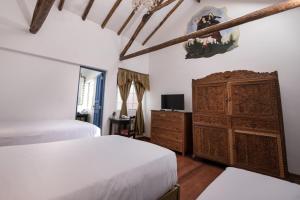 a bedroom with two beds and a wooden cabinet at Inkarri Regocijo Plaza in Cusco