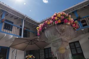 a stone vase with a flower arrangement on it with an umbrella at Inkarri Regocijo Plaza in Cusco
