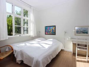 a white bedroom with a bed and a desk at Holiday home Gudhjem XLVI in Gudhjem