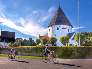 two people riding bikes down a road in front of a building at Holiday home Gudhjem XLVI in Gudhjem