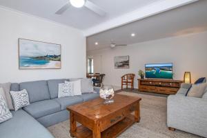 ein Wohnzimmer mit Sofa und Fernseher in der Unterkunft Evans Beach House - 24 Cedar Street in Evans Head
