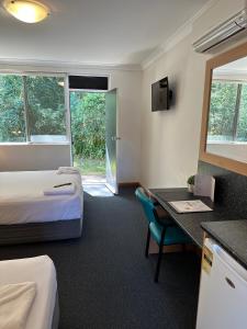 a hotel room with two beds and a desk at Bull and Bush Hotel in Medowie