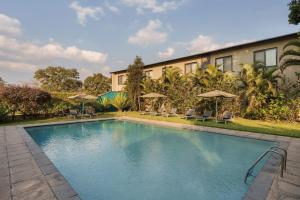 a swimming pool with chairs and umbrellas in front of a building at Protea Hotel by Marriott Ndola in Ndola