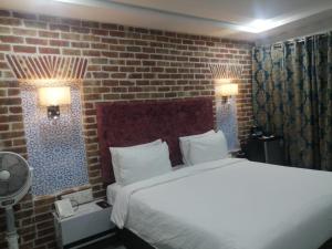 a bedroom with a bed and a brick wall at Hotel Hayatt Sukkur in Kalar Goth