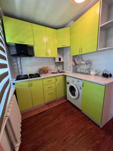 uma cozinha com armários amarelos e uma máquina de lavar roupa em Уютные апартаменты em Shymkent