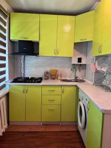 uma cozinha com armários amarelos brilhantes e uma máquina de lavar roupa em Уютные апартаменты em Shymkent