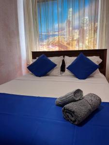 uma cama com lençóis azuis e almofadas azuis e uma janela em Уютные апартаменты em Shymkent