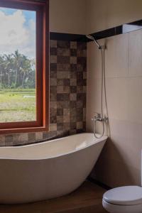 een badkamer met een bad, een toilet en een raam bij New Private Pool Villa - Villa Dhea Ubud in Ubud