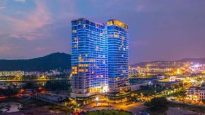 een hoog blauw gebouw met 's nachts verlichting bij Sea View Sandy homestay Citadines Marina Ha Long in Ha Long