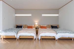 twee bedden in een kamer met houten vloeren en ramen bij PEACE OF REST SHIRAHAMA in Shirahama
