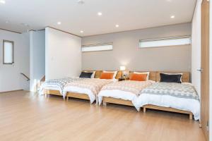 Duas camas num quarto com pisos de madeira e janelas em PEACE OF REST SHIRAHAMA em Shirahama