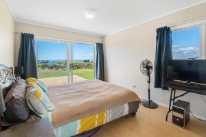 a bedroom with a bed and a large window at Tokerau Magic - Karikari Peninsula Holiday Home in Kaitaia