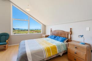 a bedroom with a bed and a large window at Tokerau Magic - Karikari Peninsula Holiday Home in Kaitaia