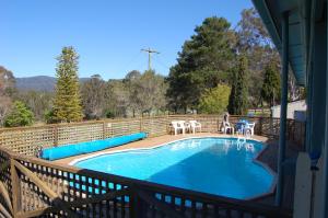 a swimming pool on a deck with a table and chairs at The Big Bell Farm in Kangaroo Valley