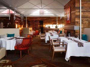 a dining room with white tables and chairs at Desert Gardens Hotel in Ayers Rock
