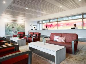 a waiting area with couches and tables in a restaurant at Desert Gardens Hotel in Ayers Rock